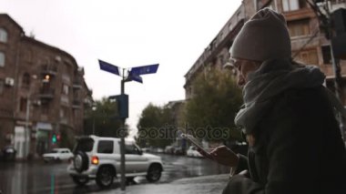 Cep telefonu sokağın yağmurlu bir akşam kasabada kullanan genç kadın