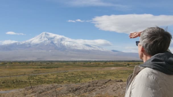 Portrait of senior man looking at mountains and pointing on them. Outdoors in mountains morning nature. — Stock Video