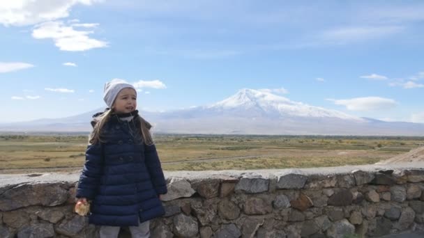 Portrait of vacation travel little girl looking at Ararat mountain landscape. Nature during summer vacations. Young kid standing at lookout looking at camera. — Stock Video