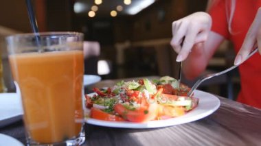 Kırmızı elbiseli bir kafede yemek eller genç kadının kapatın. Taze salata domates, salatalık, peynir ile