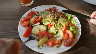 POV görünümünü eller genç kadın Kırmızı elbiseli bir kafede yemek yiyorlar. Taze salata domates, salatalık, peynir ile