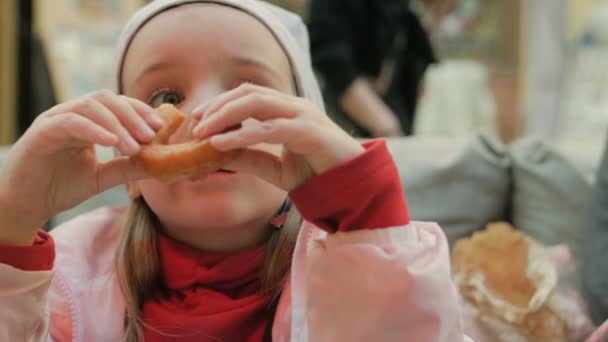 Menina come deliciosos donuts no café — Vídeo de Stock