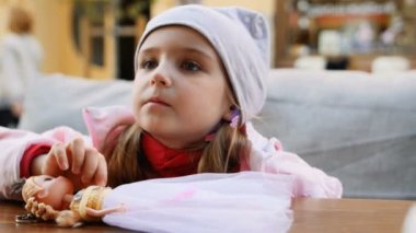 Küçük kız sokakta cafede bebek oynamak