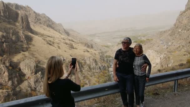 Córka biorąc zdjęcie przez telefon komórkowy, jej starszy rodziców na wakacje wycieczka w góry na przystanku road. Szczęśliwa rodzina korzystających wakacje — Wideo stockowe