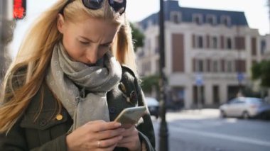Telefon, açık havada kullanan genç kadın portresi. Güneşli gün boyunca telefonla yazarak ciddi güzel genç kadın.