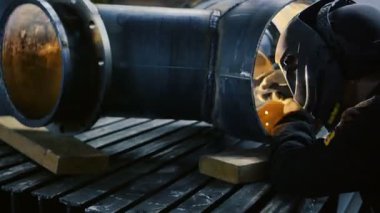 Fabrikanın içinde kaynak maskesi olan işçi. Fabrikanın içindeki ekipmanların kaynak işlemi.