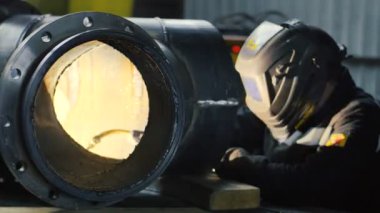 Fabrikanın içinde kaynak maskesi olan işçi. Fabrikanın içindeki ekipmanların kaynak işlemi.