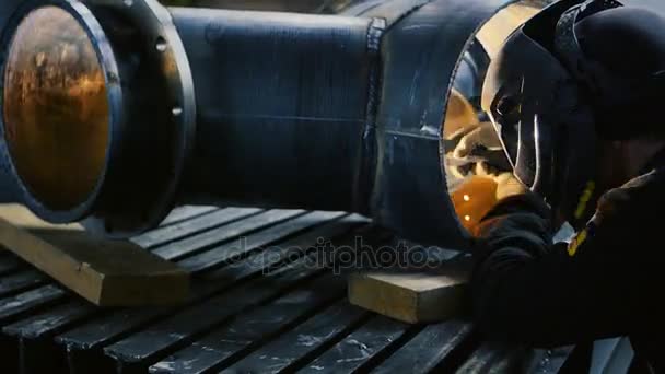 Ο εργάτης με τη μάσκα συγκόλλησης μέσα στο εργοστάσιο. Η διαδικασία συγκόλλησης ενός μέρους του εξοπλισμού μέσα στο εργοστάσιο — Αρχείο Βίντεο