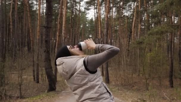 Una donna bere caffè e fare una divertente danza in movimento 4k accanto a una pineta . — Video Stock