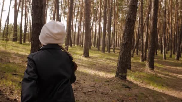 Den lilla flickan springer längs stigen i tallskogen. Klädd i skinnjacka. — Stockvideo