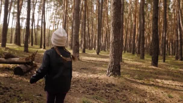 La bambina corre lungo il sentiero nella pineta. Vestita con la giacca di pelle . — Video Stock