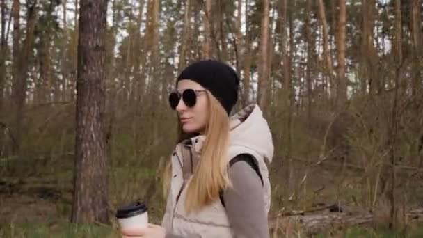 Vacker kvinna gå i skogen och dricka kaffe. 4K hög kvalitet — Stockvideo