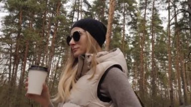 Steadycam çekim etrafında uçar. Çam ormanında kahve içen bir kadın