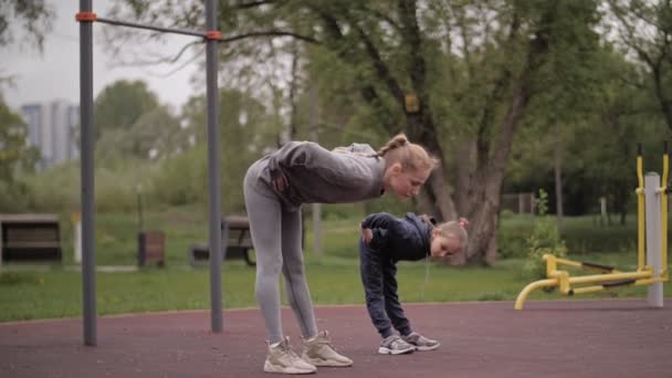 4K Moeder en dochter doen oefeningen op openlucht sport speeltuin — Stockvideo