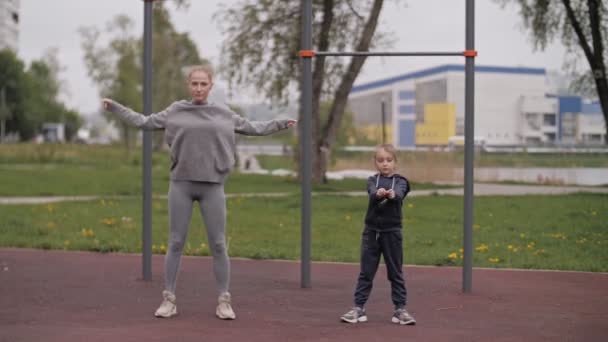 4K Madre e hija haciendo ejercicios en el patio de recreo deportivo al aire libre — Vídeo de stock