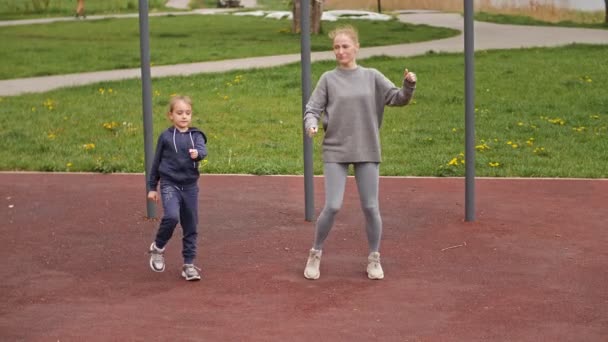 4K cámara lenta Madre e hija haciendo ejercicios en el patio de recreo deportivo al aire libre. Familia deportiva — Vídeo de stock