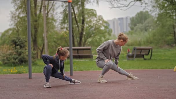 4K câmera lenta Mãe e filha fazendo exercícios em playground esporte ao ar livre. Família esportiva — Vídeo de Stock