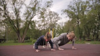 4K Anne ve Kızı açık hava sporları parkında şınav çekiyorlar.