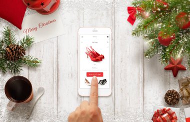 Kadın Noel zamanı sırasında cep telefonu ile ayakkabı online satın. Noel süslemeleri ile tablo