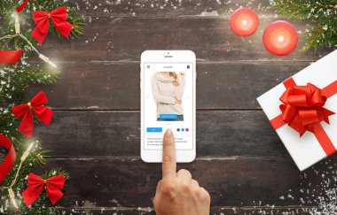 Kadın giyim online akıllı telefon ile Noel hediyesi için satın almak. Ahşap masa dekorasyon ile Noel ağacı