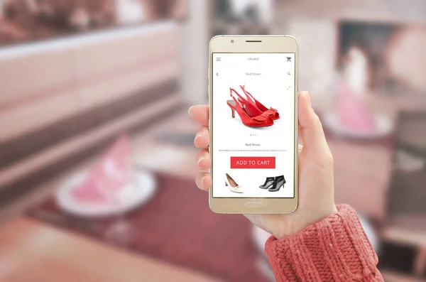 Женщина показывает современный золотой смартфон с приложением онлайн покупок на дисплее устройства — стоковое фото