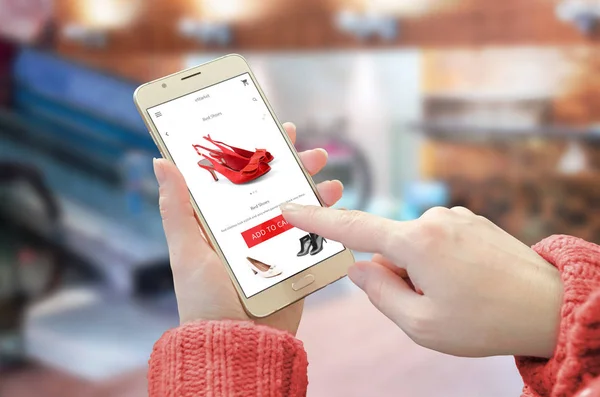 Shopping web site app on smart phone. Woman holding mobile device and buy red shoes — Stock Photo, Image