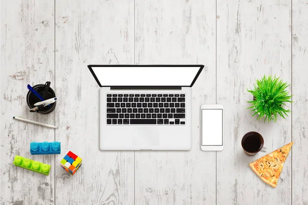 Laptop on white wooden table. Top view of creative clean office desk with pens, plant, coffee, color cubes beside.