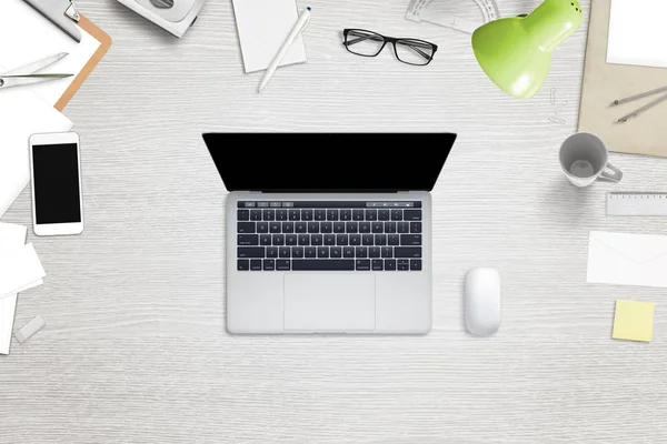 Top view of laptop and work desk with a lot of stationery. Smart phone, mug, glasses beside. — Stock Photo, Image