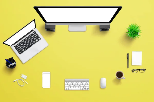 Yellow office desk with computer display, laptop, and mobile phone — Stock Photo, Image