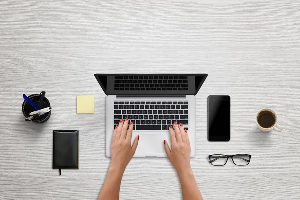 Frau tippt auf Laptop-Tastatur. leerer Bildschirm für Mockup, Design-Präsentation. Moderne Büroszene mit schwarzem Smartphone daneben — Stockfoto