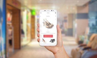 Cep telefonu ekranda online alışveriş. Modern beyaz akıllı telefon ile yuvarlak kenarları kız elinde. Arka planda alışveriş merkezi