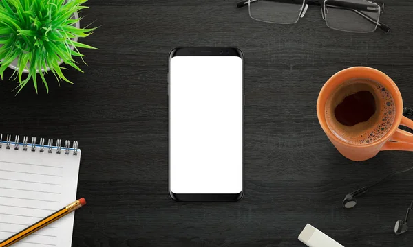 Moderne mobiele telefoon mockup. Zwarte slimme telefoon op zwarte houten bureau omringd met plant met koffie, pad, potlood, bril — Stockfoto