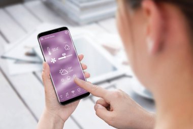 Kadın kullanım akıllı ev kontrol app üstünde hareket eden telefon.