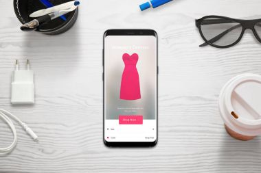 Bir cep telefonu ile alışveriş online. Kadın seçin boyutu ve elbisesinin rengiyle mağaza app. üstten görünüm hareket eden ve Resepsiyon.