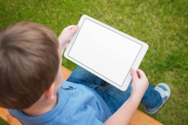 Çocuk mockup için izole beyaz ekran ile tablet kullanın. Sörf ya da çizgi film izlerken oyun oynayan çocuk.
