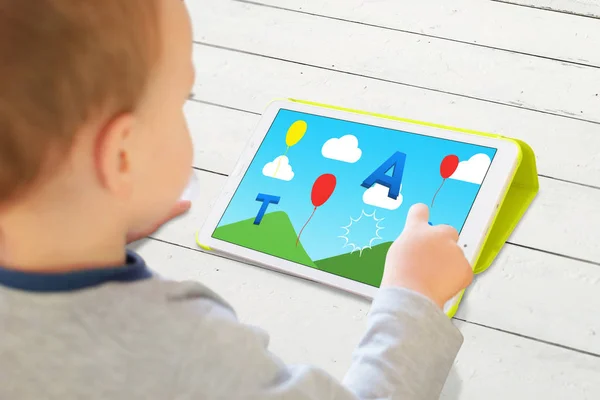 Kind spelen spel met letters op een tablet. Moderne app voor de ontwikkeling van kinderen vaardigheden — Stockfoto