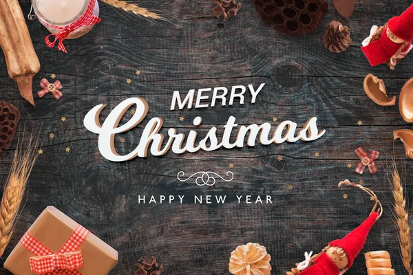 Feliz Navidad y feliz año nuevo texto en escritorio de madera negro con decoraciones de Navidad — Foto de Stock