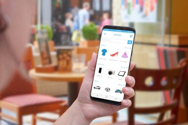 Online alışveriş ile akıllı telefon. Kadın akıllı telefon tutun. Kahve dükkanında arka plan.