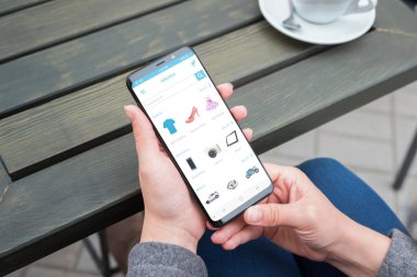 Web Mağazalar ile modern akıllı telefon üzerinde yuvarlak kenarları kadın elinde.