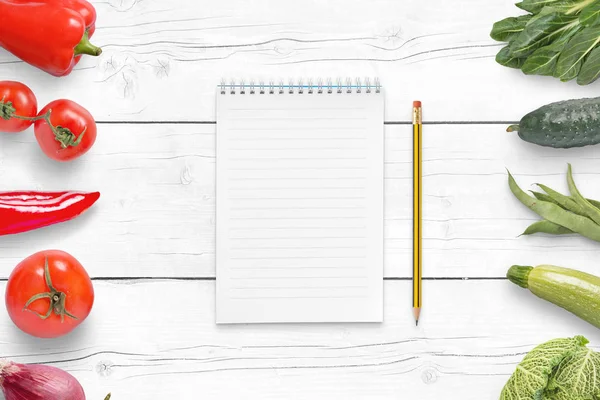 Boş panel malzemeler Beyaz ahşap masa üzerinde bir listesi için. Kırmızı ve yeşil sebze yanında.