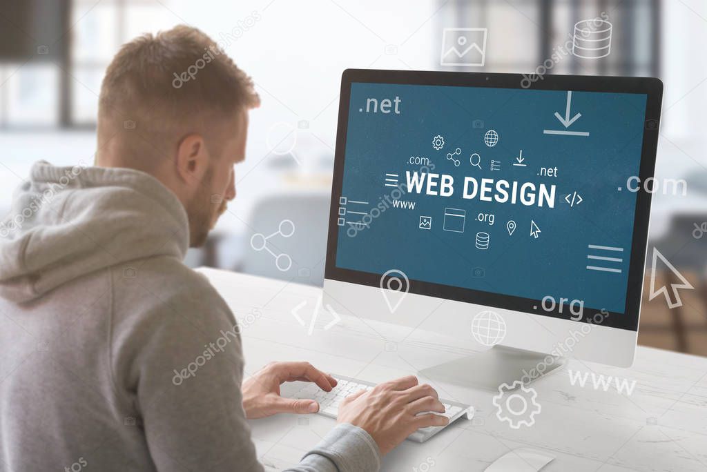 Web design studio concept. Guy work on computer with Web design text surrounded by web site parts and domain extensions.
