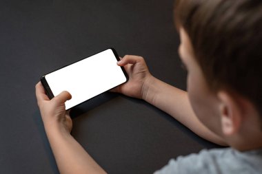 Erkek ellerindeki telefon modeli. Oyun için izole edilmiş ekranı olan yatay konum, uygulama tanıtımı. Omzunun üstünden bak. Arkaplanda siyah masa