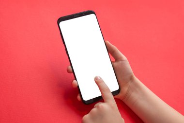 Çocuk ellerinde telefon maketi. Dikey pozisyonda. Oyun için izole ekran, uygulama tanıtımı. Arka planda kırmızı masa