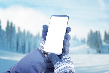 Eldivenli akıllı telefon. Yürüyüş rotası planlamak için cep telefonu kullanma kavramı. Arkasında kar olan dağ