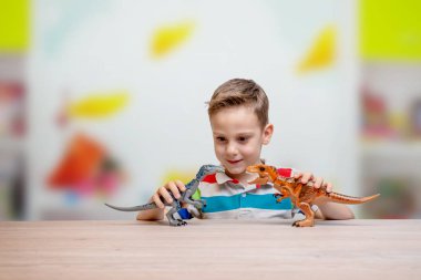 Çocuk dinozorlarla oynuyor. Öğrenme kavramı ve çocukların zeka gelişimi. Arka plandaki çocuk odası.