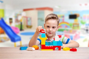 Çocuk tuğlalarla oynuyor. Gelişim kavramı çocukların motor becerileri ve hayal gücü. Arka planda çocuk oyun odası