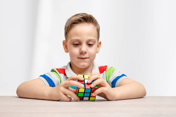 Kid assembles a rubik cube. Concept of hobby, play and solving puzzles. Close-up