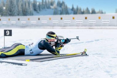 Biatlet 20 km 'lik bir yarışta yalan söylüyor ve bir hedefi vuruyor. Yarışma için modern spor ekipmanlarına sahip bir atlet