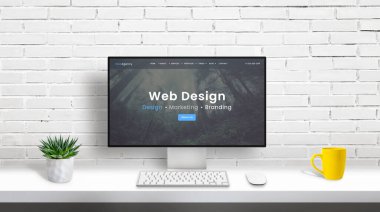 Web tasarım stüdyosu konsepti, bilgisayar ekranı ve web tasarım ajansı web sayfası. Bitki, klavye, fare ve kahve kupası olan temiz bir masa. Arkaplanda beyaz tuğla duvar