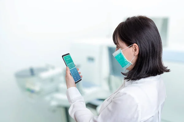 Woman in a hospital lab holds a phone with the findings of a patient who is positive for a corona virus concept